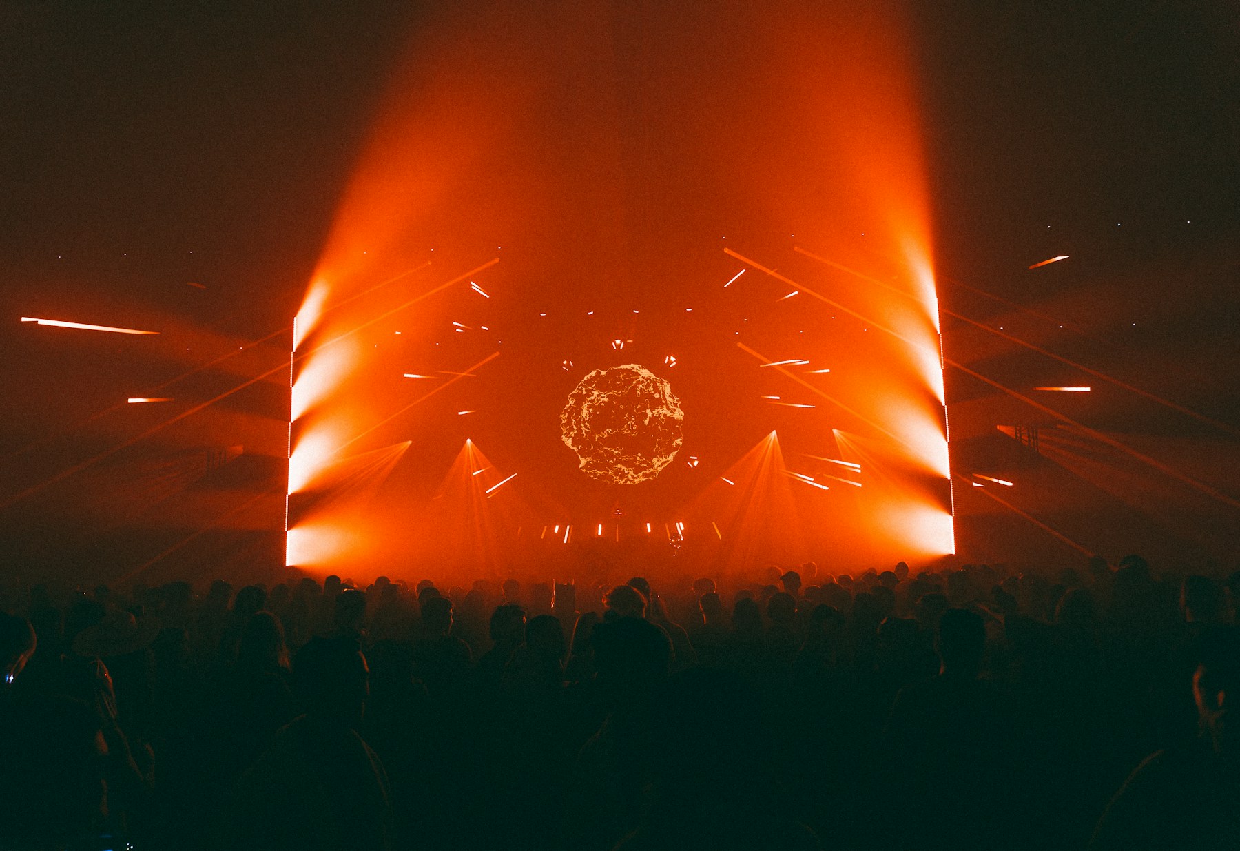 A real concert crowd facing a stage illuminated by orange lights