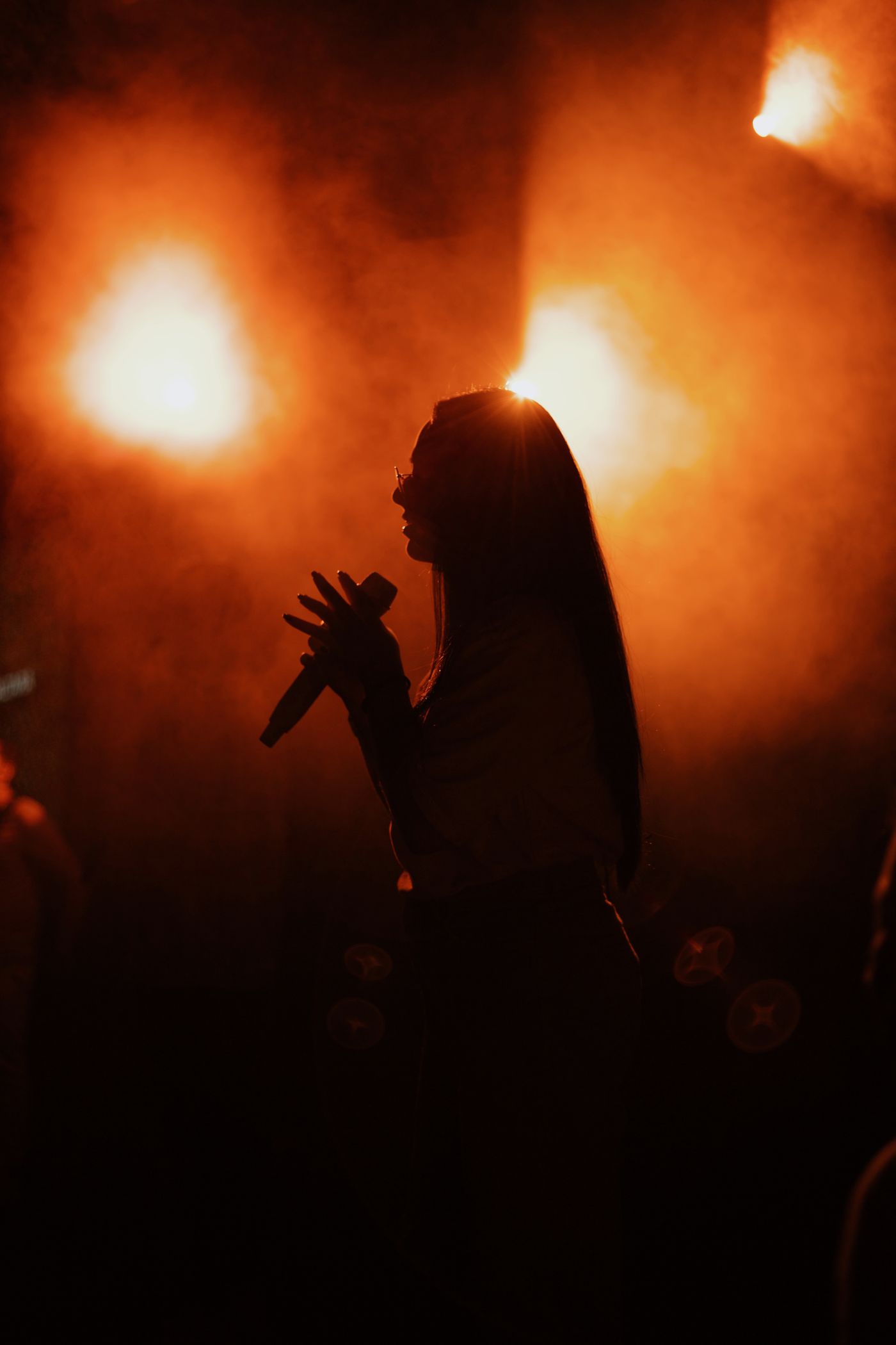 A singer performing in silhouette under warm orange stage lights
